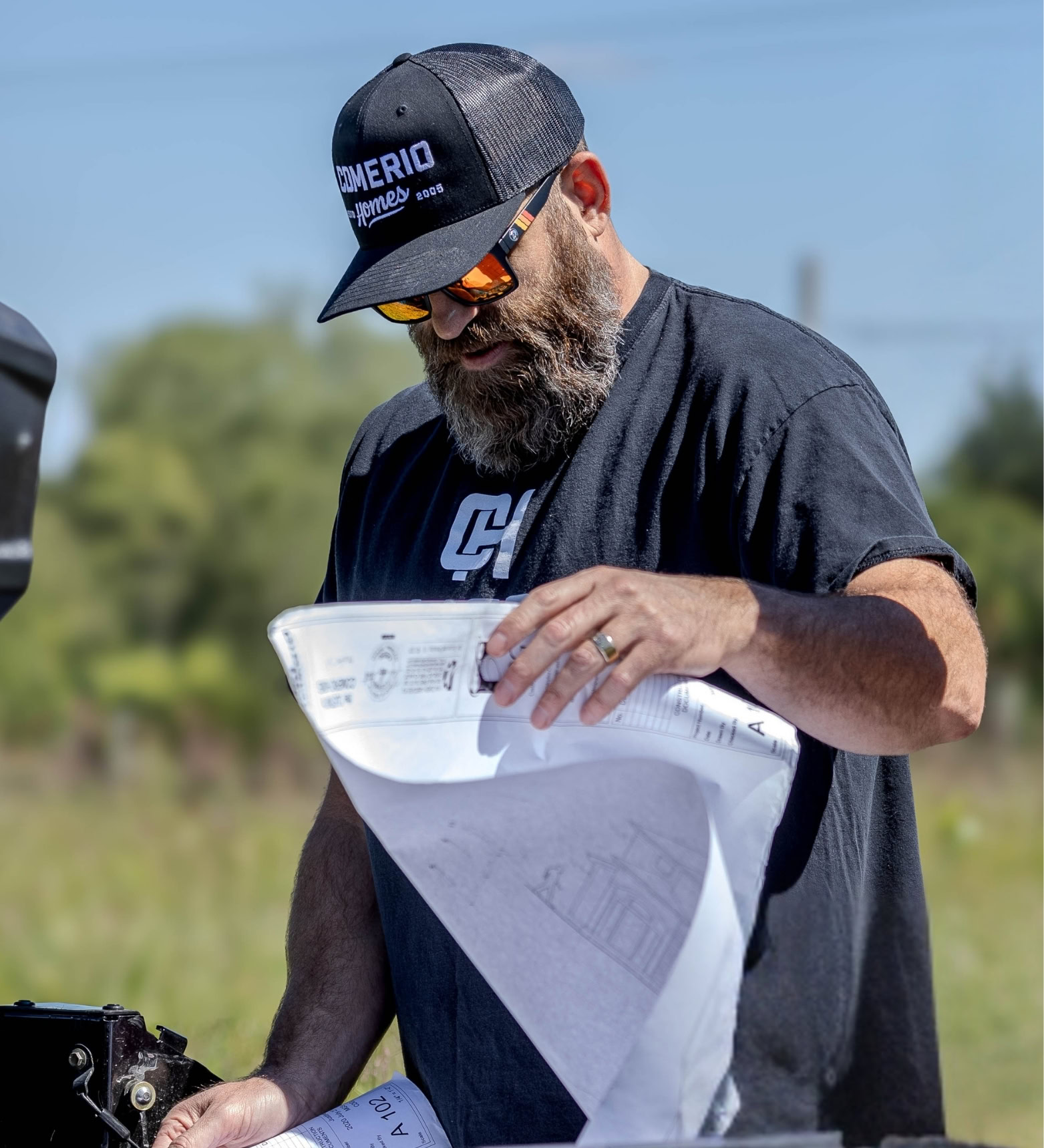 Damon Comerio reviewing plans on a project site)